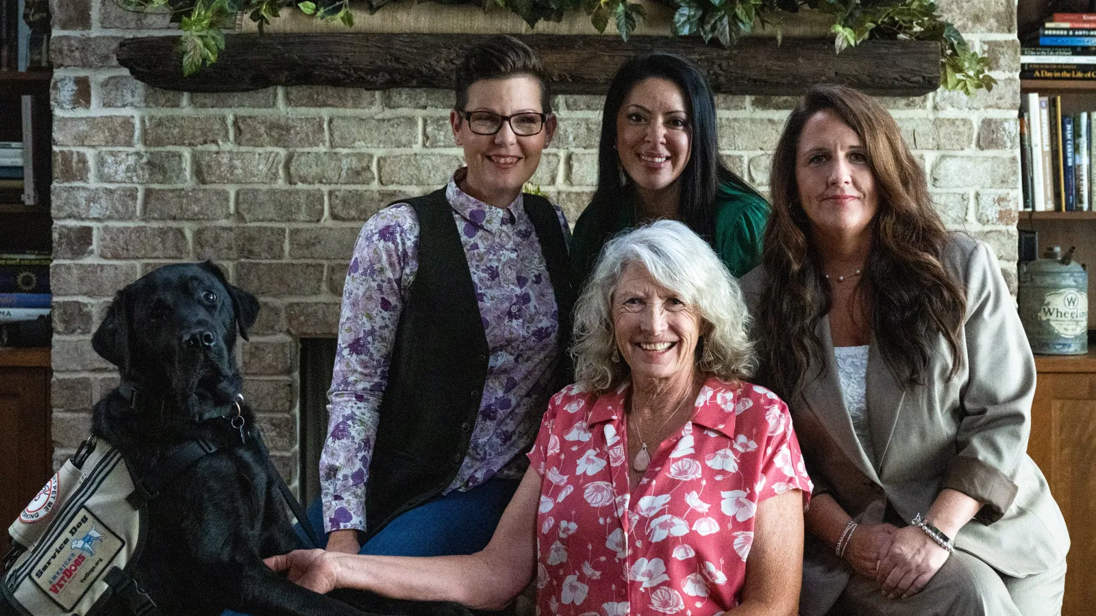 Stacy Pearsall and her service dog, Charlie, smile for a group picture with Stephanie Gattas, Colleen Bushnell, and Connie Osier. 