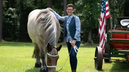 Stacy Pearsall and one of her horses smiling next to the American flag.
